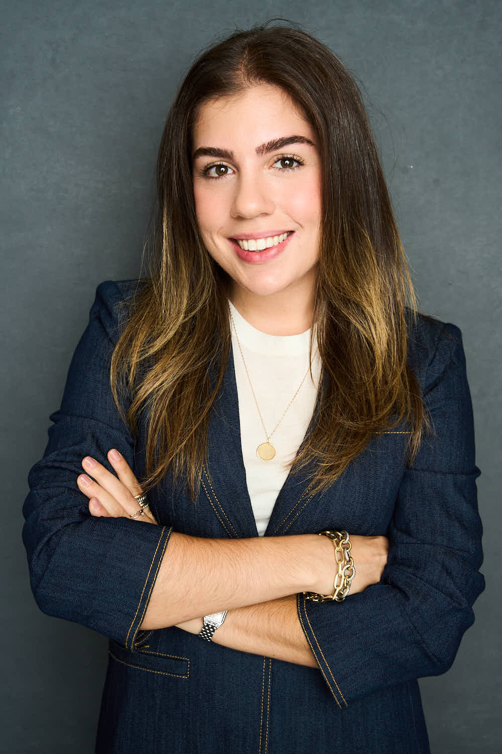 Clarissa Rosen, arms crossed, wearing a navy blazer over a white top.